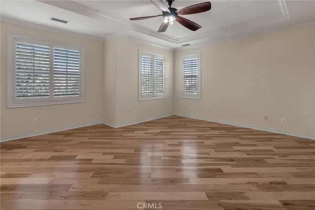 a view of empty room with wooden floor and fan