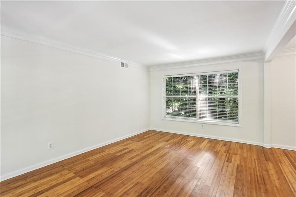 311 Peachtree Hills Avenue Northeast, Unit 13B Atlanta, GA 30305 - Photo 9 of 30 an empty room with wooden floor and windows