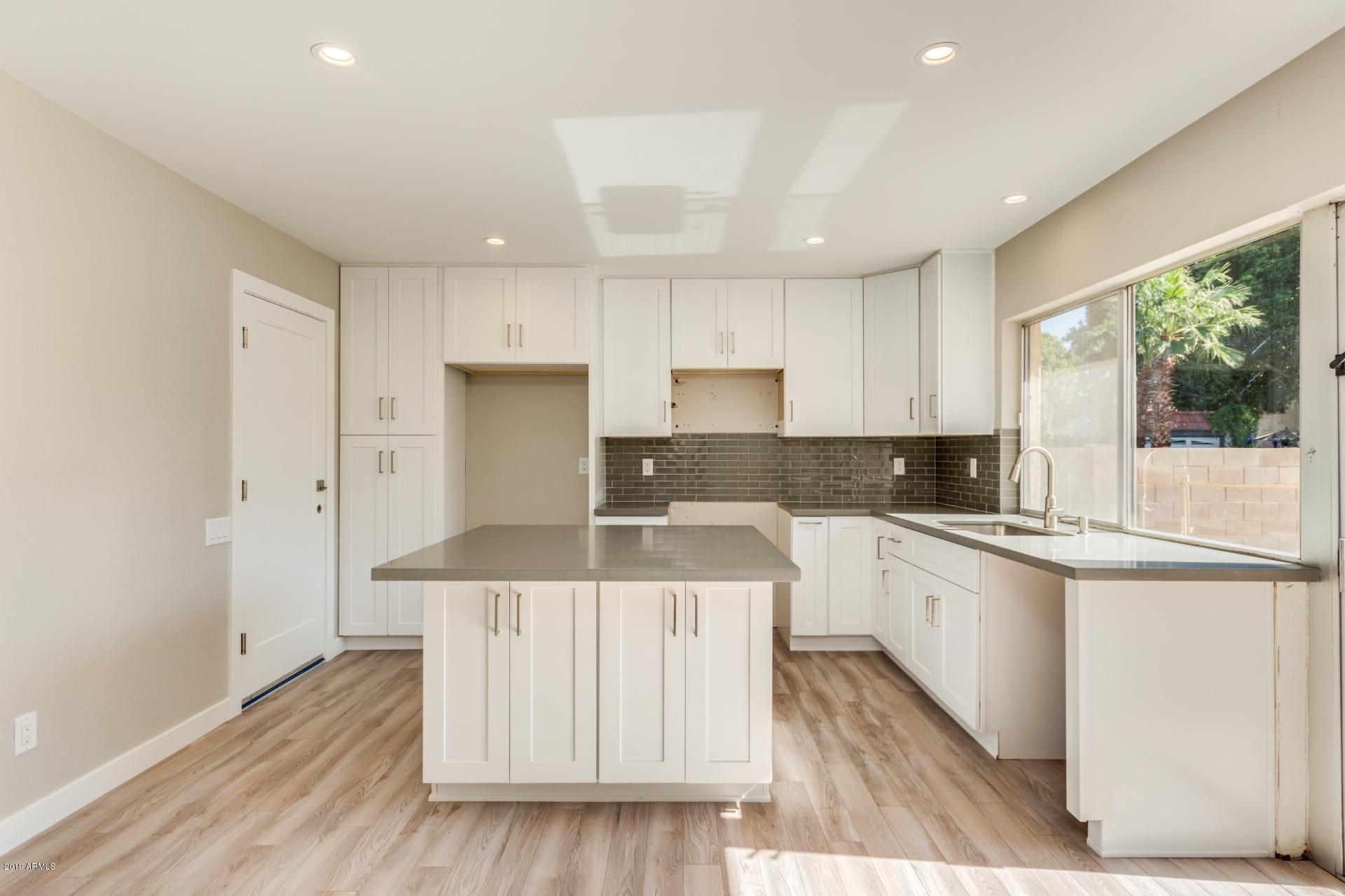 5503 South Rocky Point Road Tempe, AZ 85283 - Photo 2 of 22 a kitchen with a sink a stove a refrigerator and white cabinets with wooden floor