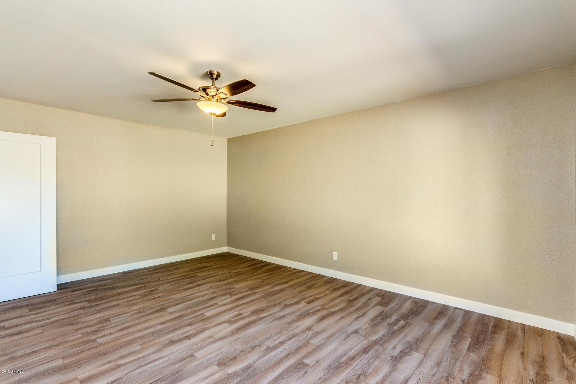 5503 South Rocky Point Road Tempe, AZ 85283 - Photo 4 of 22 a view of a room with wooden floor and a ceiling fan