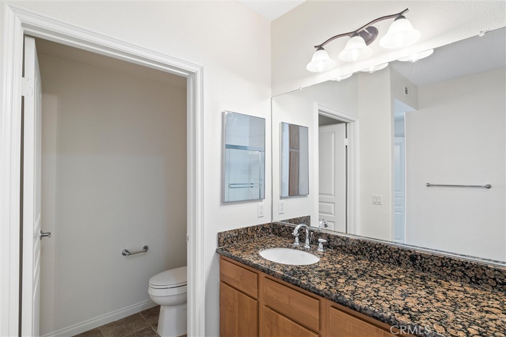 12688 Chapman Avenue, Unit 3201 Garden Grove, CA 92840 - Photo 17 of 17 a bathroom with a granite countertop sink a toilet and a mirror