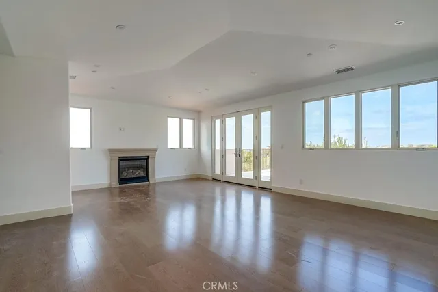 an empty room with wooden floor fireplace and windows