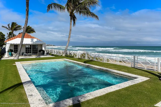 a view of a swimming pool with a lawn chairs under palm trees