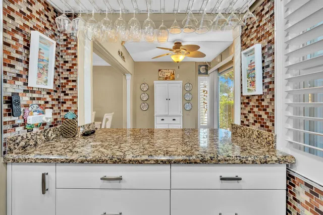 a bathroom with a granite countertop toilet a sink a mirror and a window