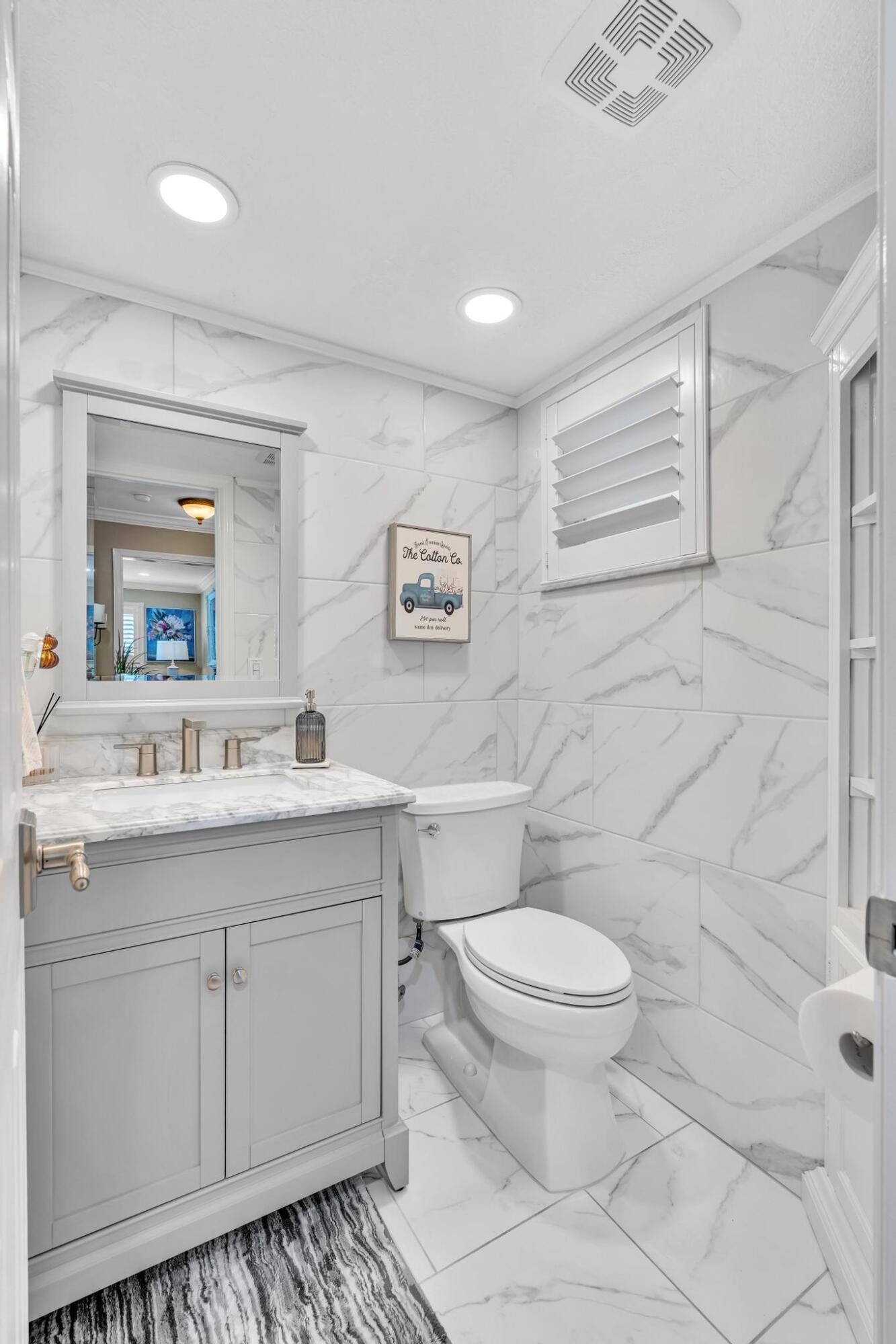 34 Colonial Club Drive, Unit 101 Boynton Beach, FL 33435 - Photo 24 of 58 a bathroom with a granite countertop toilet a sink a mirror and a window