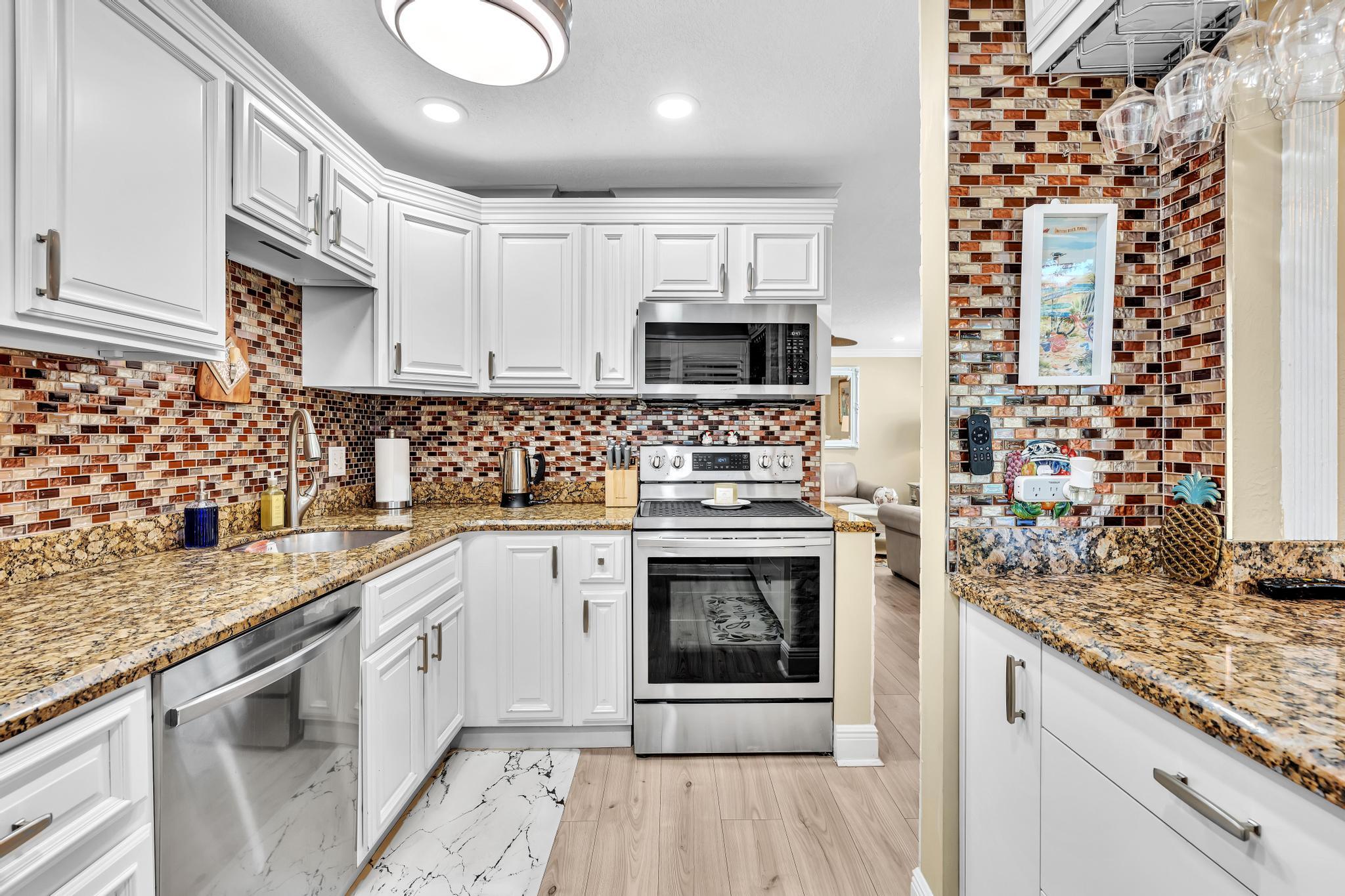 34 Colonial Club Drive, Unit 101 Boynton Beach, FL 33435 - Photo 6 of 58 a kitchen with granite countertop a stove sink and cabinets
