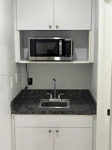 a kitchen with granite countertop white cabinets and stainless steel appliances
