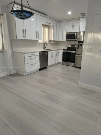 a kitchen with stainless steel appliances a stove a sink dishwasher a refrigerator and cabinets with wooden floor