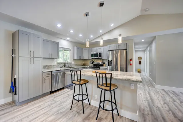 a kitchen with kitchen island wooden floors white appliances and cabinets