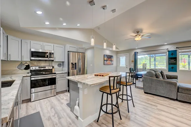 a living room with stainless steel appliances kitchen island granite countertop furniture and a fireplace