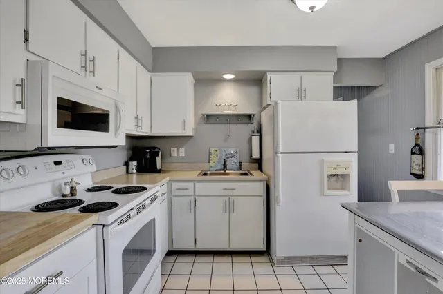 a kitchen with a sink a stove a refrigerator and white cabinets