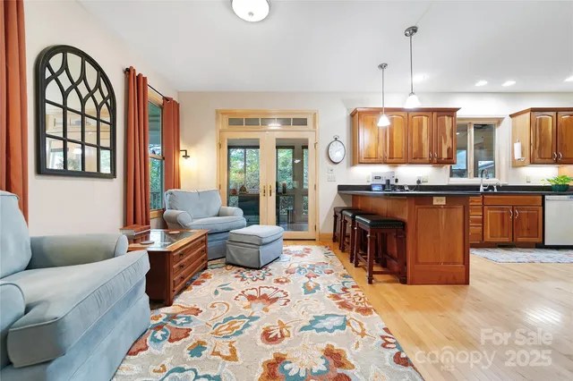 a living room with stainless steel appliances granite countertop a stove a sink dishwasher a dining table and chair with wooden floor