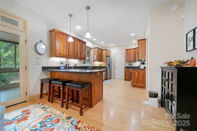 a kitchen with stainless steel appliances granite countertop a refrigerator a sink dishwasher a stove and a dining table with wooden floor