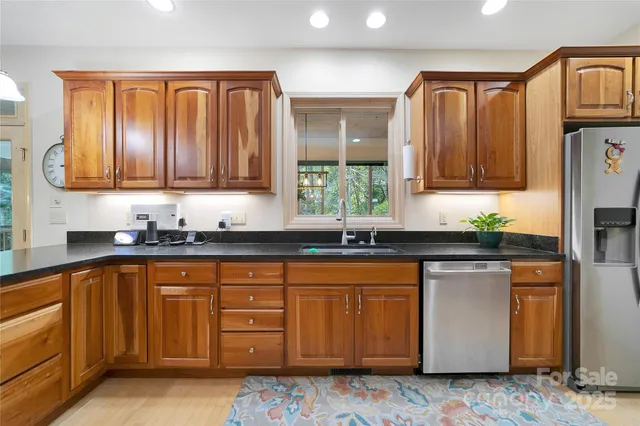 a kitchen with stainless steel appliances granite countertop a sink a stove a refrigerator and cabinets