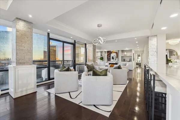 a living room with lots of furniture kitchen view and a wooden floor