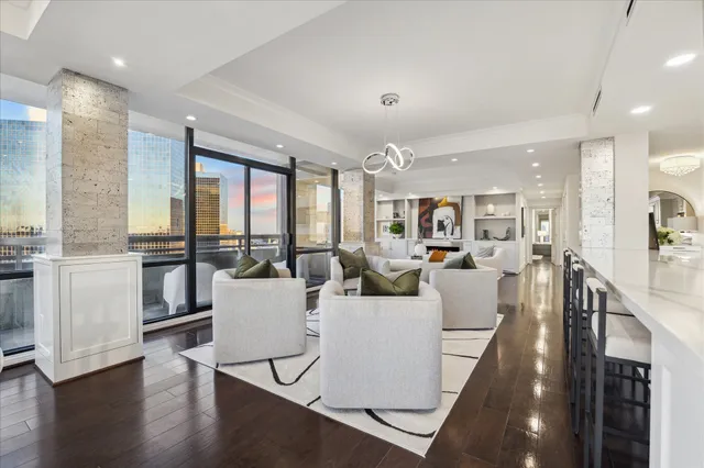 a living room with lots of furniture kitchen view and a wooden floor