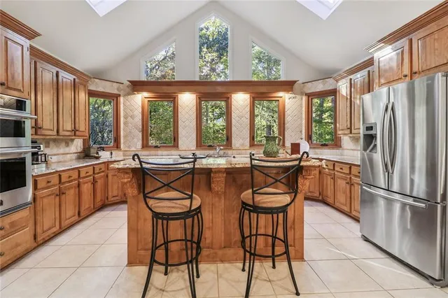 a kitchen with stainless steel appliances granite countertop a stove a refrigerator a sink dishwasher a dining table and chairs with wooden floor