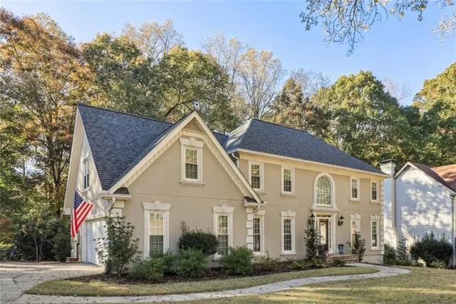 a view of a white house with a tree and plants