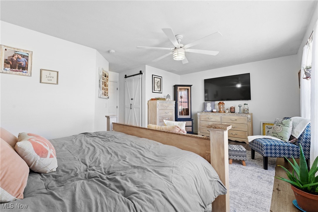 4038 Gardiner Run Akron, OH 44321 - Photo 27 of 38 Bedroom with a barn door, wood finished floors, and a ceiling fan