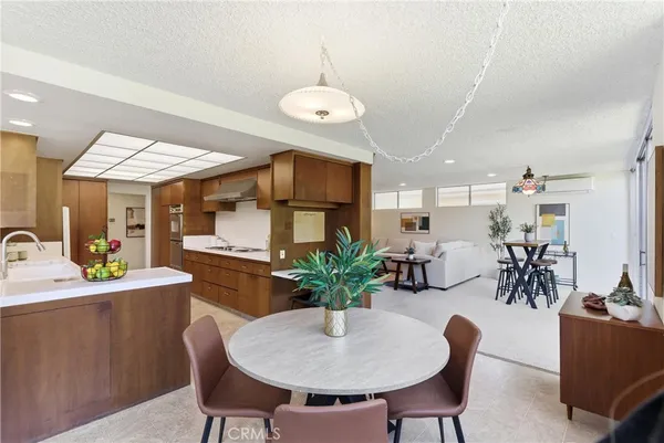 a view of a dining room and livingroom with furniture wooden floor a rug a flat screen tv a rug and a chandelier
