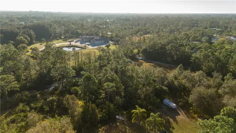 an aerial view of residential houses with outdoor space and trees