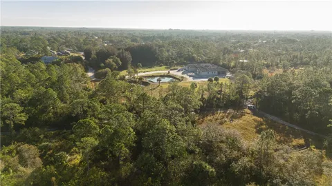 an aerial view of residential houses with outdoor space and trees