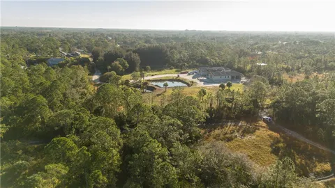 an aerial view of residential houses with outdoor space and trees