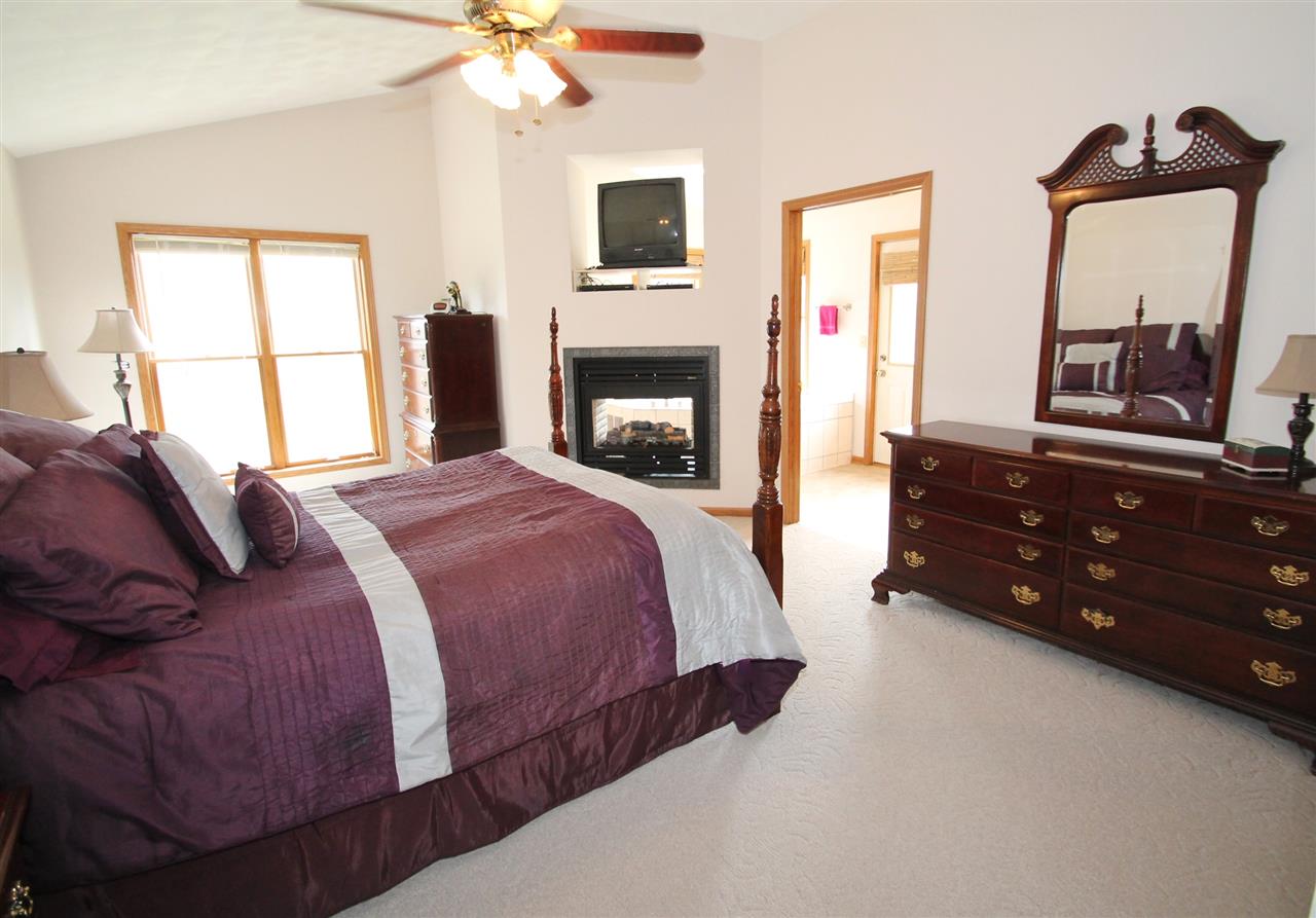 4461 Ridgeview Lane Byron, IL 61010 - Photo 13 of 25 a spacious bedroom with a bed and a flat tv screen on dresser