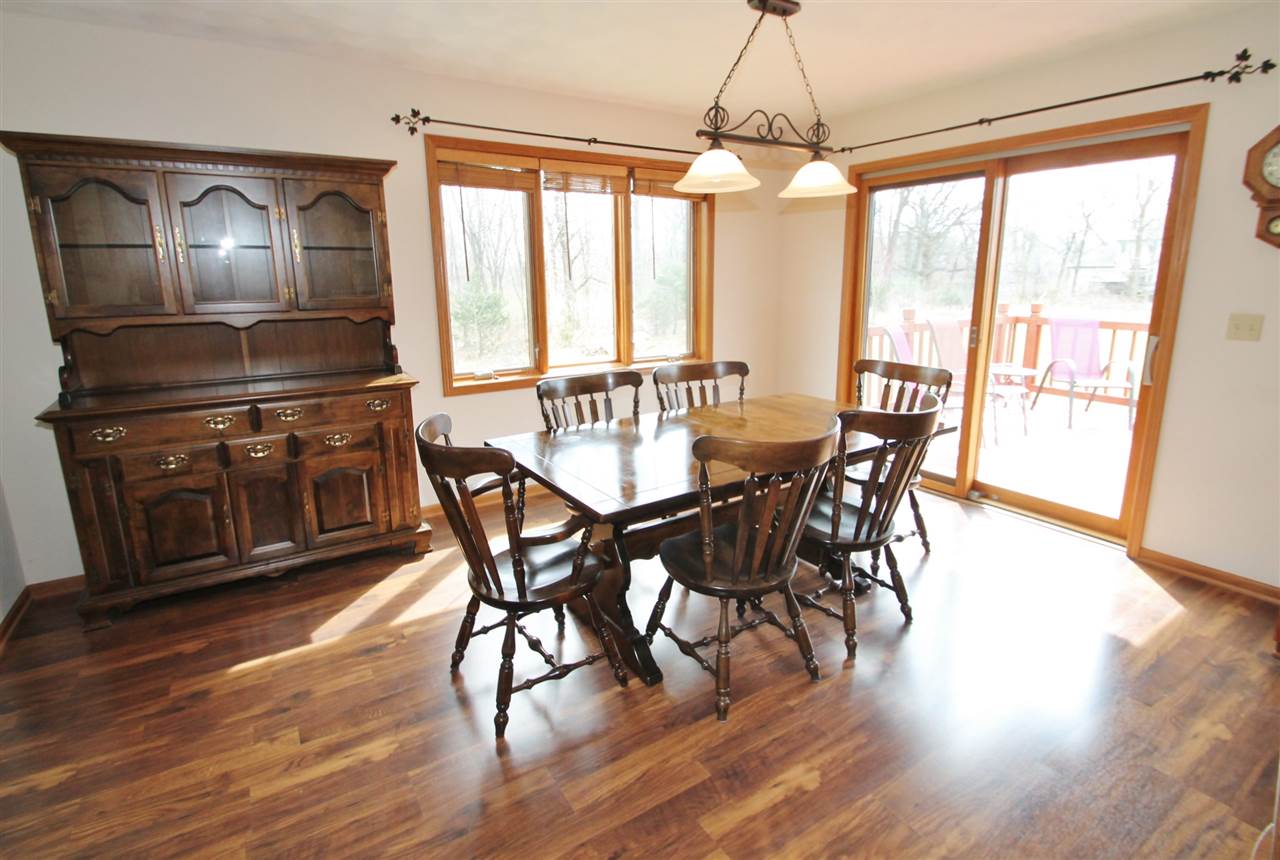 4461 Ridgeview Lane Byron, IL 61010 - Photo 7 of 25 a dining room with wooden floor a chandelier a glass table and chairs