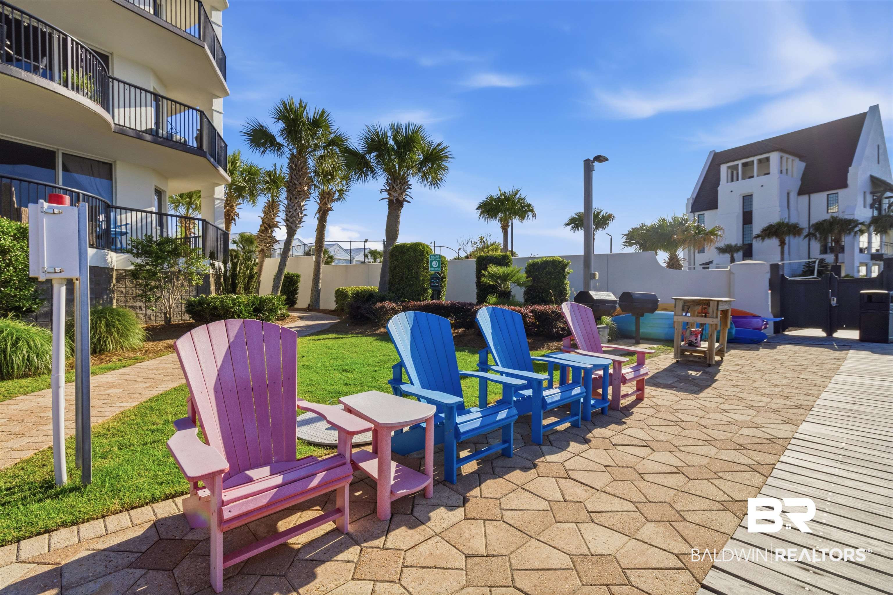 3564 Bayou Road, Unit 203 Orange Beach, AL 36561 - Photo 39 of 53 Landscaped outdoor area featuring a paver patio, a wooden boardwalk, and a grassy expanse with tropical palm trees