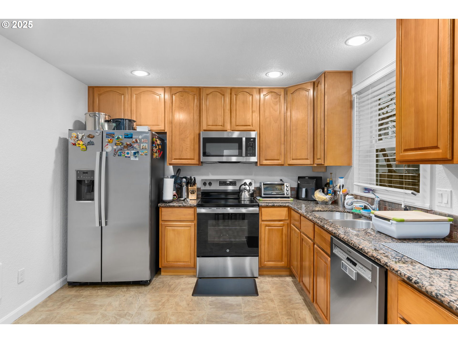 11938 Southeast Market Street Portland, OR 97216 - Photo 12 of 28 a kitchen with stainless steel appliances granite countertop a refrigerator a sink a stove a microwave and island