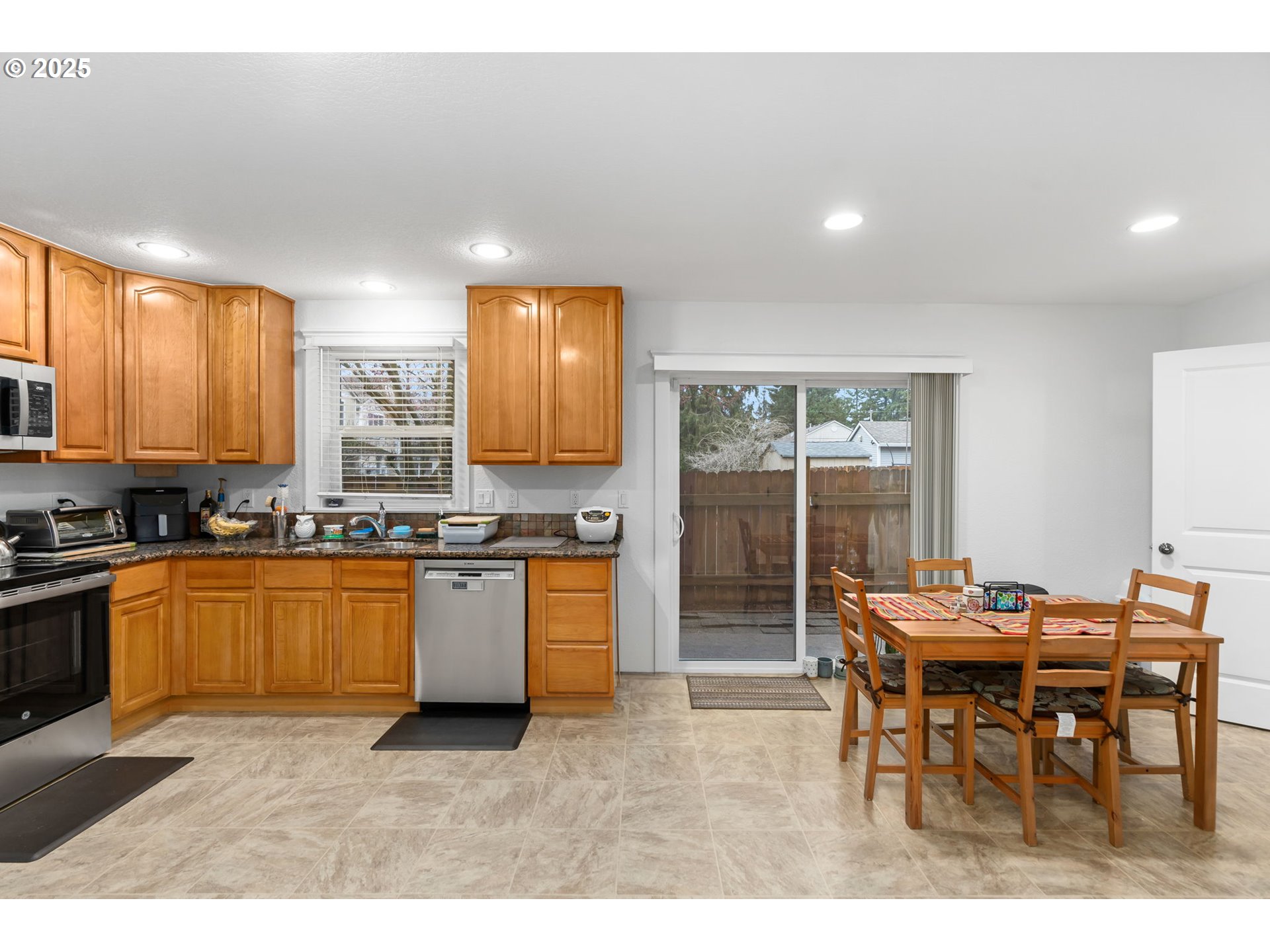 11938 Southeast Market Street Portland, OR 97216 - Photo 10 of 28 a kitchen with stainless steel appliances kitchen island granite countertop a dining table chairs and granite counter tops