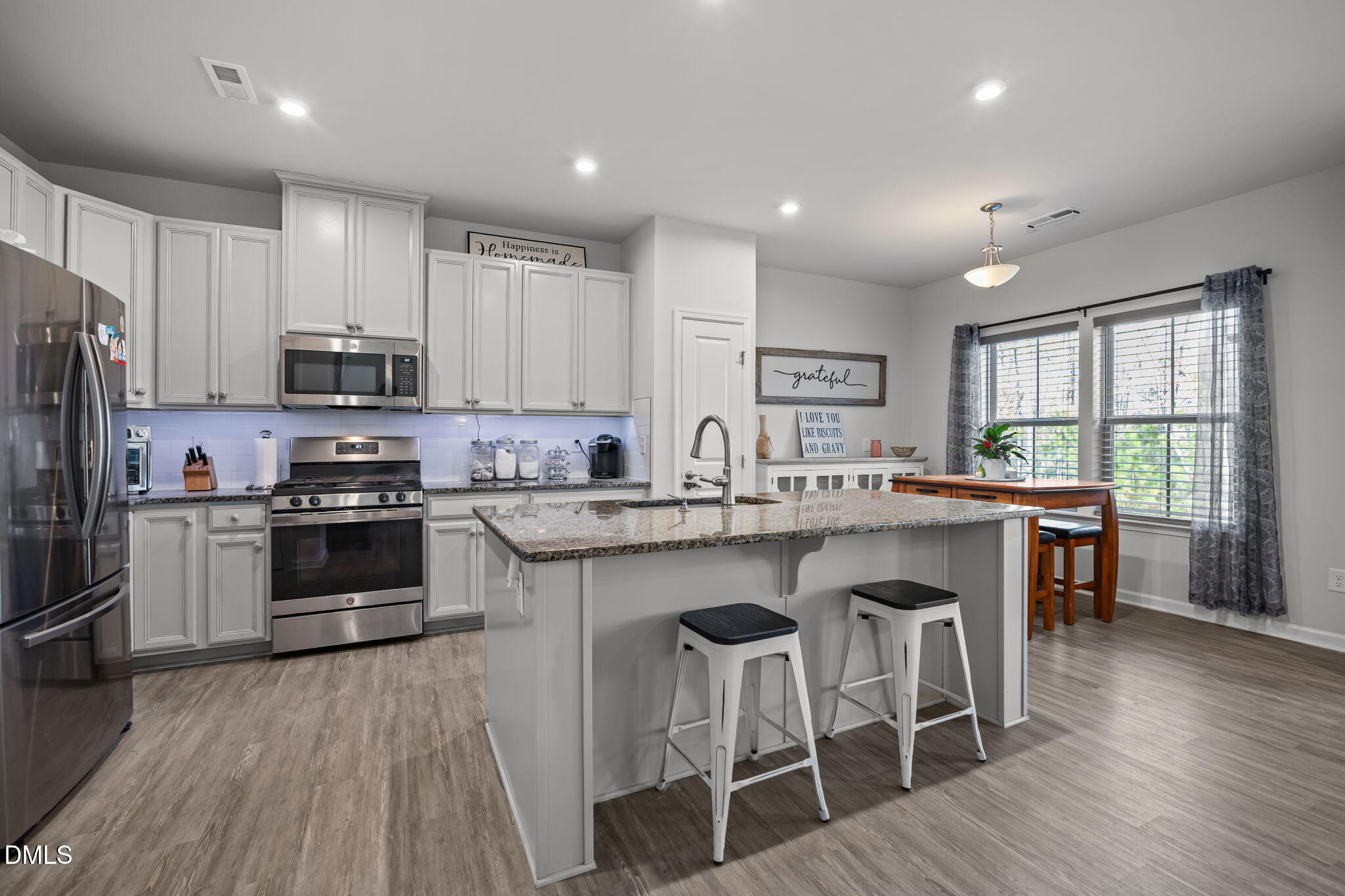1624 Ripley Woods Street Wake Forest, NC 27587 - Photo 11 of 41 a kitchen with granite countertop stainless steel appliances a stove a sink a refrigerator cabinets and a dining table with wooden floor