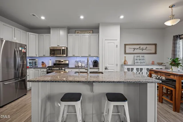 a kitchen with stainless steel appliances granite countertop a sink a stove a refrigerator cabinets and chairs