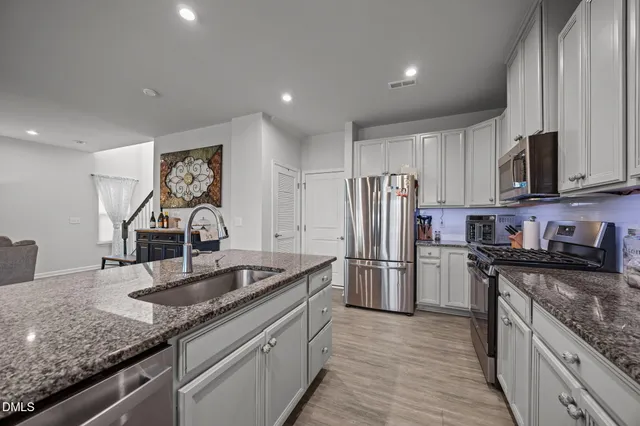 a kitchen with stainless steel appliances granite countertop a sink stove and refrigerator