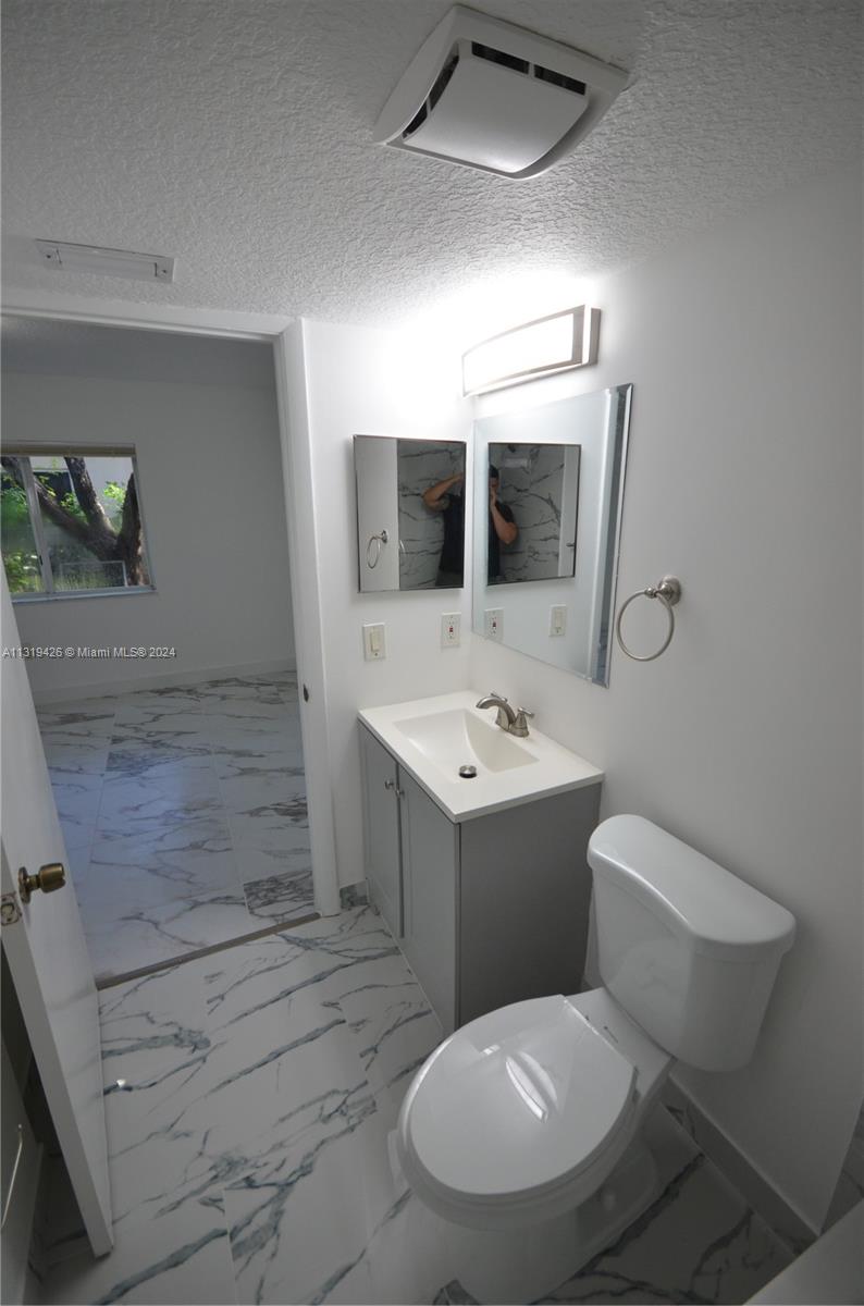 1241 Southeast 29th Street, Unit 102 Homestead, FL 33035 - Photo 21 of 23 a bathroom with a toilet sink and mirror