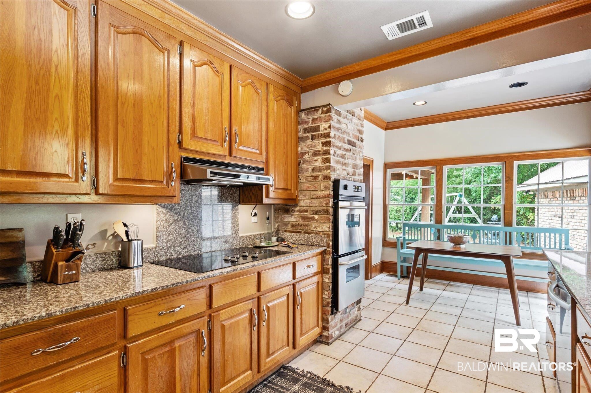 2228 Riverside Drive Mobile, AL 36605 - Photo 18 of 51 Kitchen featuring black electric stovetop, ornamental molding, light stone countertops, double oven, and light tile patterned flooring