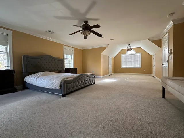 a spacious bedroom with a bed a window and a chandelier