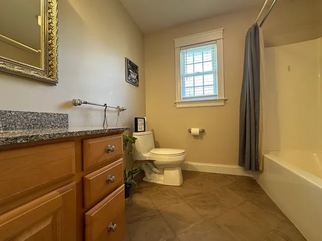 a bathroom with a granite countertop toilet sink and mirror
