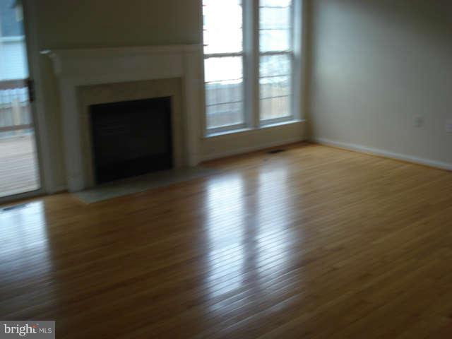 104 Limited Drive Ranson, WV 25438 - Photo 3 of 13 an empty room with wooden floor fireplace and windows