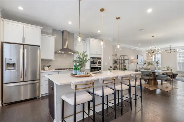 a kitchen with stainless steel appliances kitchen island granite countertop a dining table chairs and white cabinets