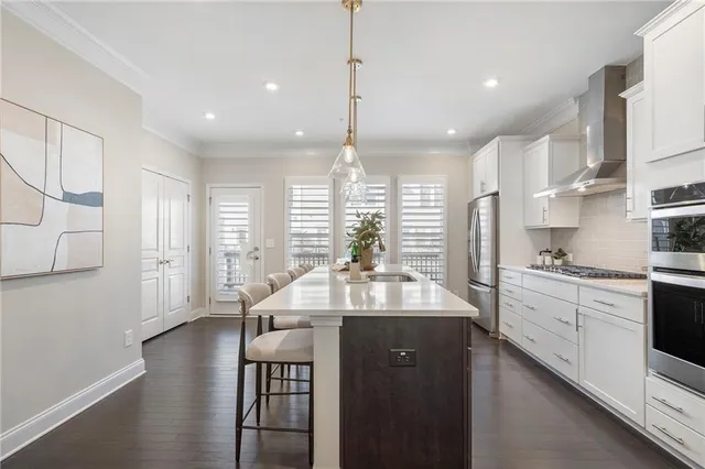 a kitchen with stainless steel appliances kitchen island granite countertop a sink dishwasher a stove and white cabinets with wooden floor