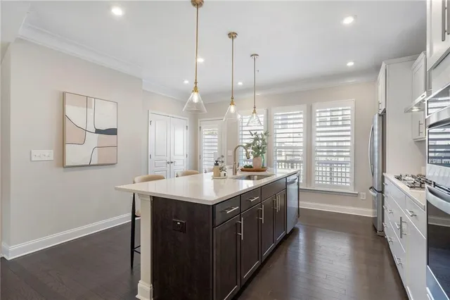 a kitchen with stainless steel appliances granite countertop a sink a stove a kitchen island and a window