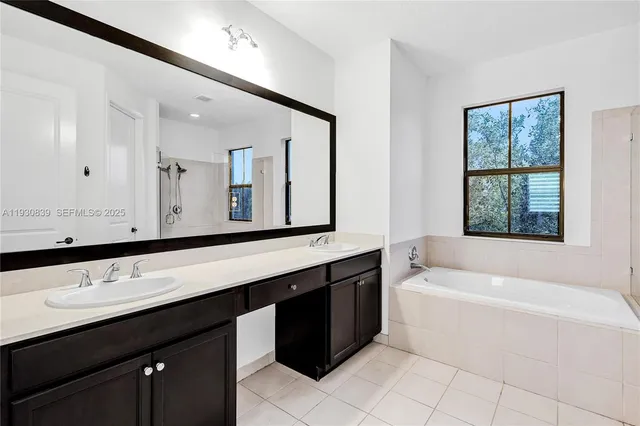 a bathroom with a bathtub a double vanity sink and mirror