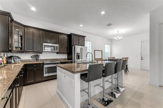 a kitchen with stainless steel appliances granite countertop a sink a stove a refrigerator cabinets and chairs