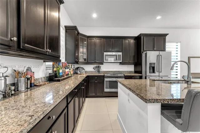 a kitchen with stainless steel appliances granite countertop a sink a stove and a refrigerator
