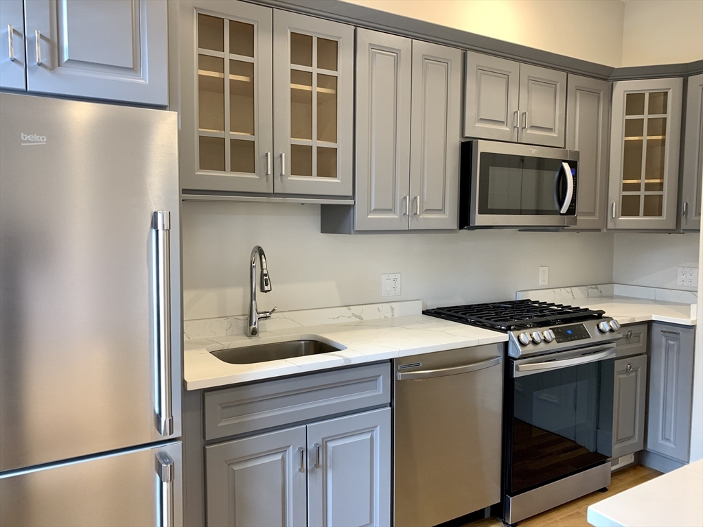 354 Marlborough Street, Unit 2 Boston, MA 02115 - Photo 4 of 10 a kitchen with stainless steel appliances white cabinets and a stove top oven