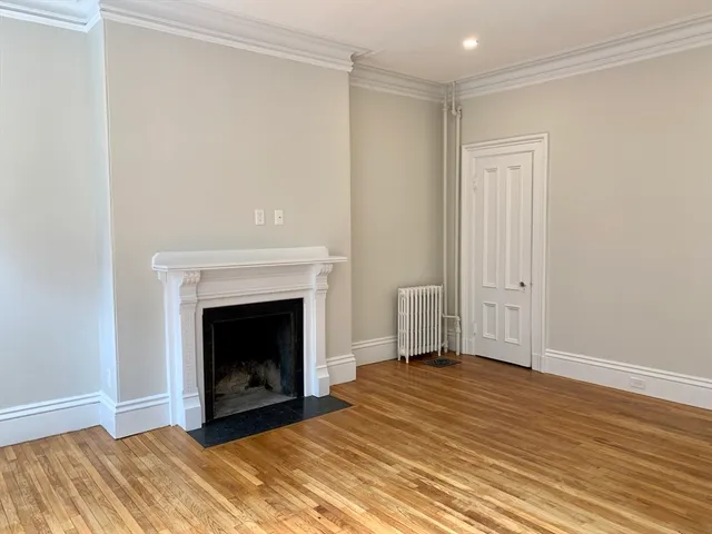 a view of empty room with wooden floor and fireplace