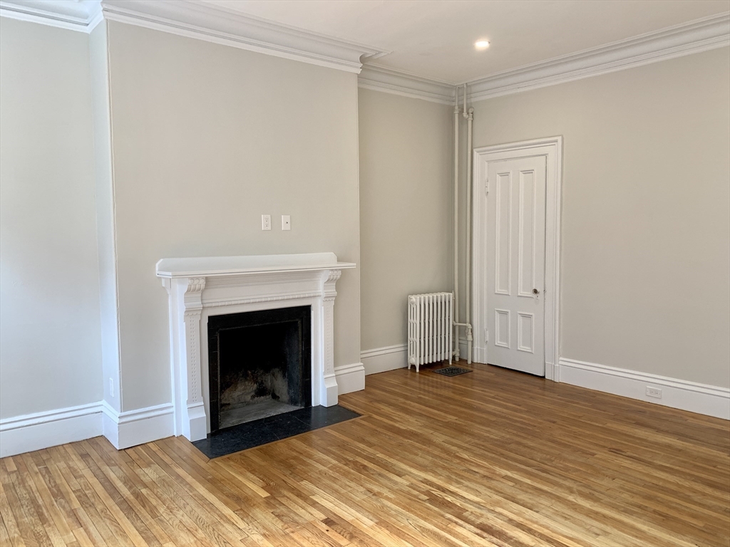 354 Marlborough Street, Unit 2 Boston, MA 02115 - Photo 8 of 10 a view of empty room with wooden floor and fireplace