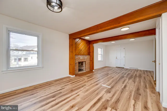 an empty room with wooden floor and fireplace